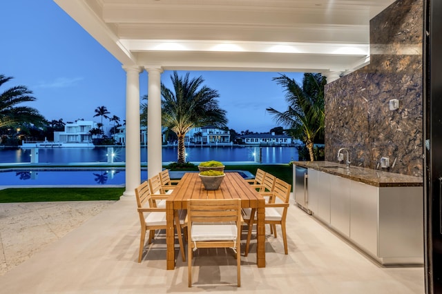 patio terrace at dusk with sink and a water view