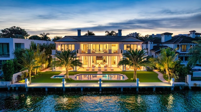 back house at dusk with a balcony and a water view