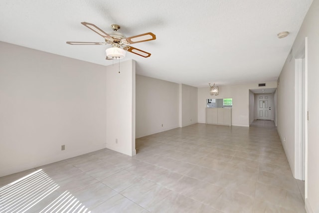 unfurnished living room with a textured ceiling, ceiling fan with notable chandelier, and light tile patterned floors