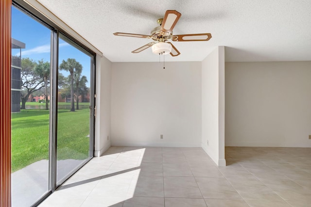 unfurnished room with a textured ceiling, light tile patterned flooring, and ceiling fan