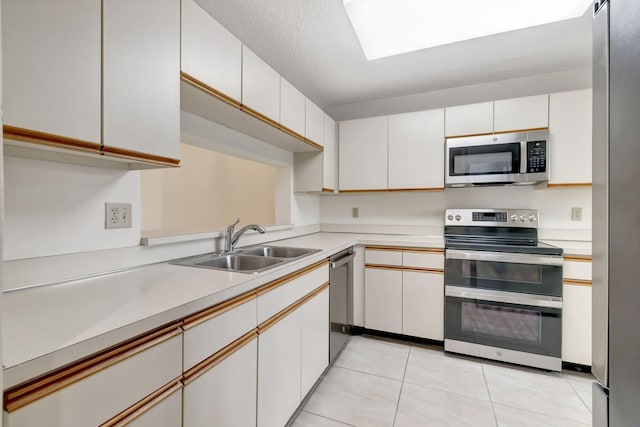 kitchen with a textured ceiling, sink, white cabinets, stainless steel appliances, and light tile patterned floors