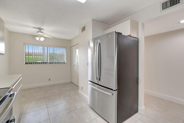 kitchen with a textured ceiling, white cabinetry, appliances with stainless steel finishes, light tile patterned floors, and ceiling fan