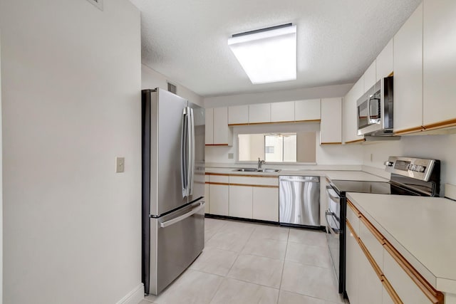 kitchen with appliances with stainless steel finishes, a textured ceiling, sink, and white cabinets