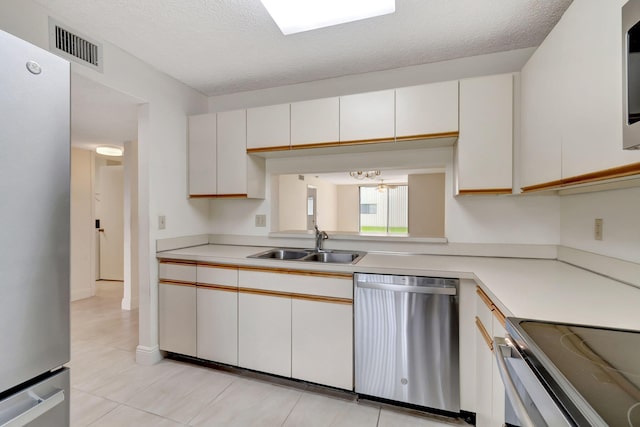 kitchen with white cabinetry, a textured ceiling, appliances with stainless steel finishes, and sink