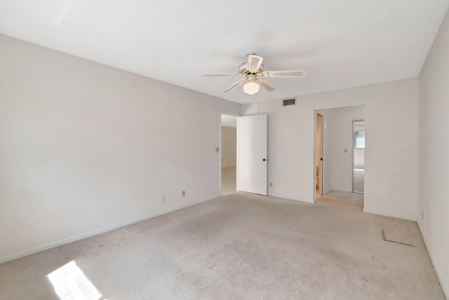 unfurnished bedroom with ceiling fan, light colored carpet, and connected bathroom