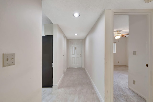 corridor featuring light colored carpet and a textured ceiling