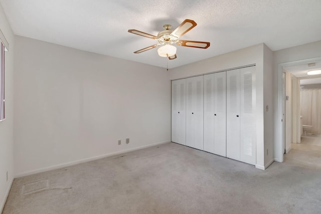 unfurnished bedroom featuring ceiling fan, a textured ceiling, a closet, and light carpet