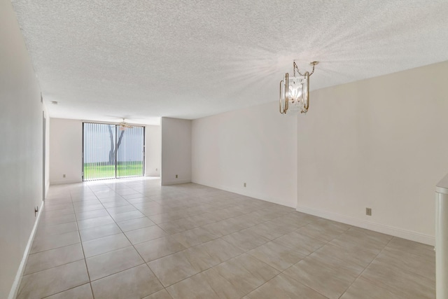 tiled empty room with a chandelier, a textured ceiling, and expansive windows