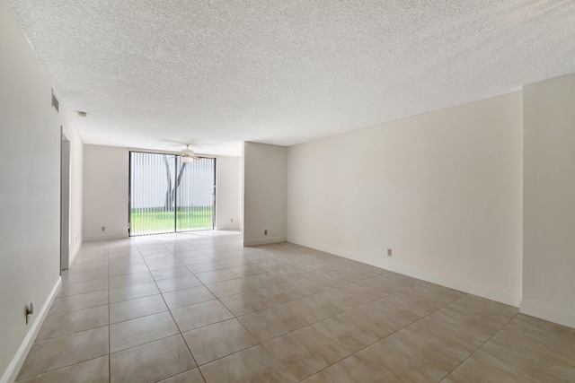 tiled spare room featuring a textured ceiling, ceiling fan, and expansive windows