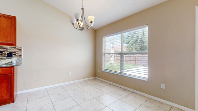 unfurnished dining area featuring light tile patterned floors, a textured ceiling, and an inviting chandelier