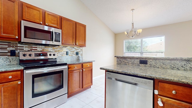 kitchen with light stone countertops, appliances with stainless steel finishes, backsplash, vaulted ceiling, and a chandelier