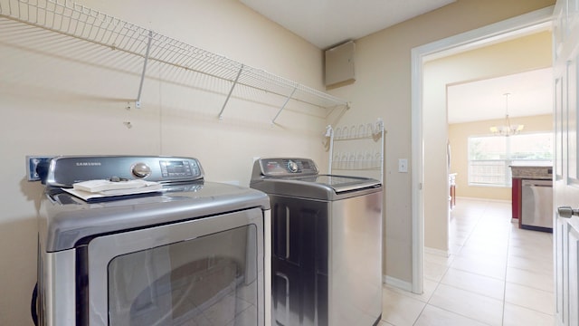 washroom featuring washer and clothes dryer, a notable chandelier, and light tile patterned flooring