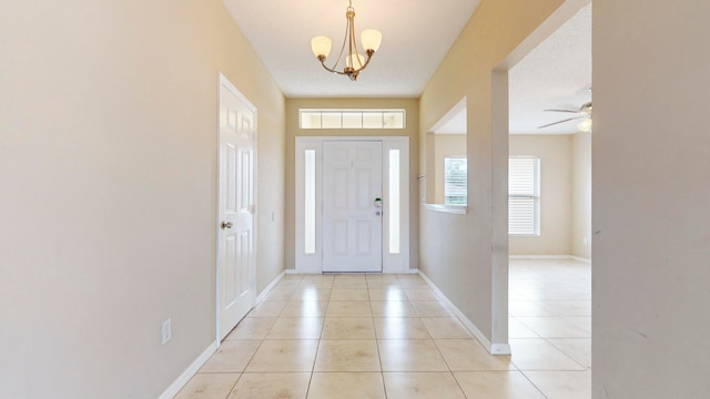 tiled entryway with ceiling fan with notable chandelier and a textured ceiling