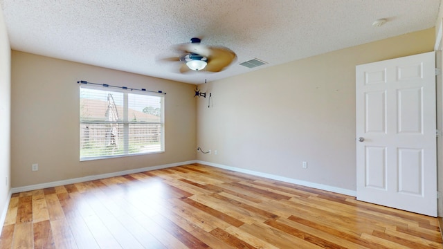 spare room featuring ceiling fan, light hardwood / wood-style floors, and a textured ceiling