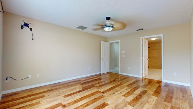 unfurnished bedroom with ceiling fan, light wood-type flooring, a textured ceiling, and connected bathroom