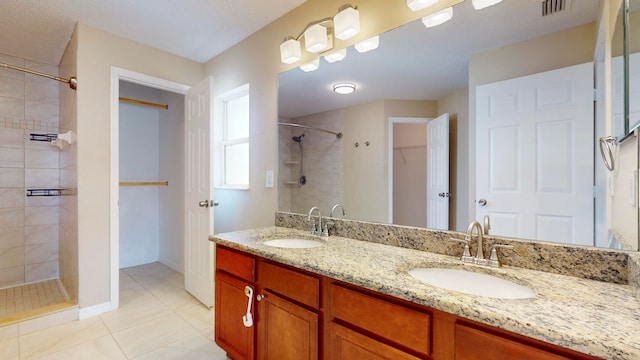 bathroom featuring a tile shower, vanity, and tile patterned floors