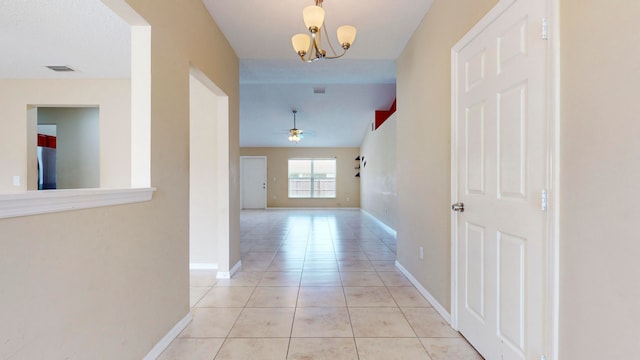 corridor with a notable chandelier and light tile patterned flooring