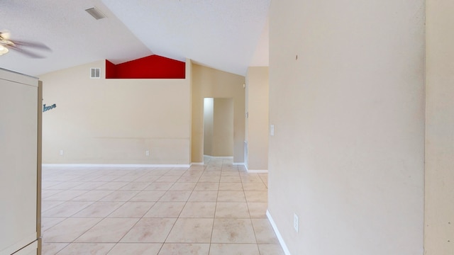 spare room featuring a textured ceiling, ceiling fan, light tile patterned floors, and vaulted ceiling