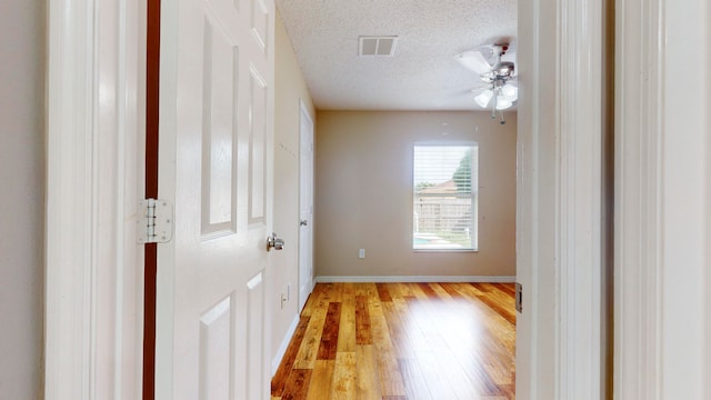 unfurnished room featuring ceiling fan, light hardwood / wood-style flooring, and a textured ceiling