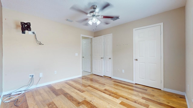 unfurnished bedroom featuring multiple closets, ceiling fan, and light hardwood / wood-style floors