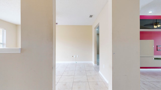 hallway with light tile patterned flooring and a textured ceiling