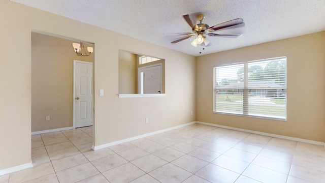 empty room with ceiling fan with notable chandelier, light tile patterned flooring, and a textured ceiling