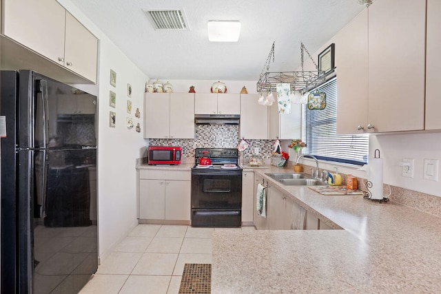 kitchen with sink, cream cabinets, decorative backsplash, light tile patterned floors, and black appliances