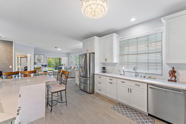 kitchen with a healthy amount of sunlight, white cabinetry, sink, and stainless steel appliances