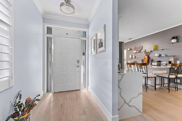 entrance foyer with light wood-type flooring, crown molding, and wood walls