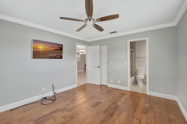 unfurnished bedroom featuring wood-type flooring, ceiling fan with notable chandelier, connected bathroom, and crown molding