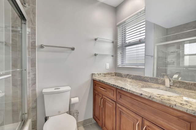 bathroom with vanity, a shower with shower door, and toilet