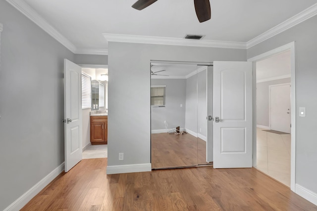 unfurnished bedroom with ceiling fan, a closet, light wood-type flooring, and ornamental molding