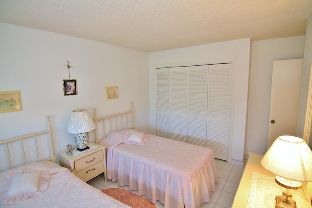 tiled bedroom with a textured ceiling and a closet