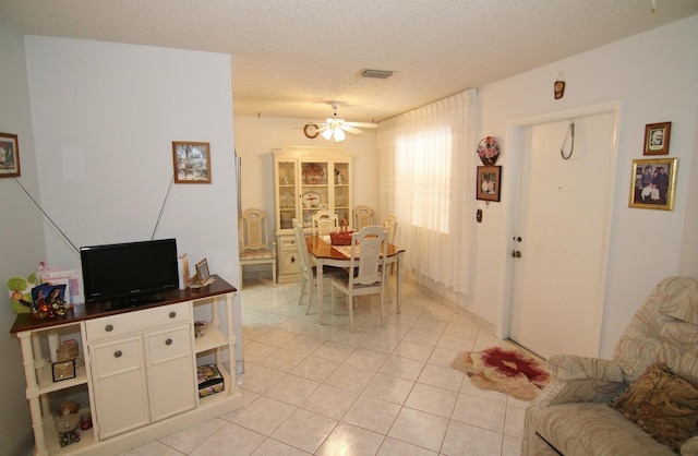 living room with ceiling fan, light tile patterned flooring, and a textured ceiling