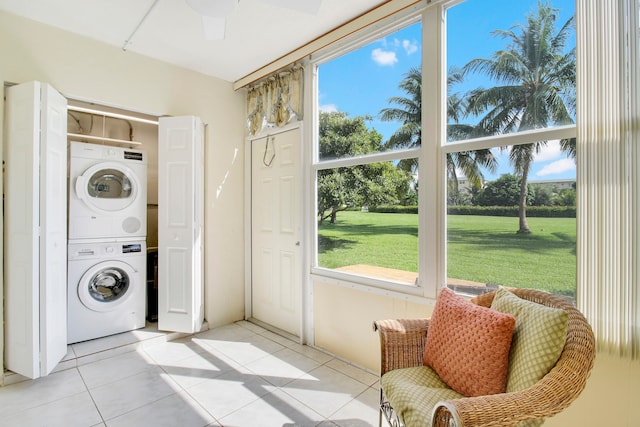 washroom featuring a wealth of natural light, ceiling fan, stacked washer / dryer, and light tile patterned flooring