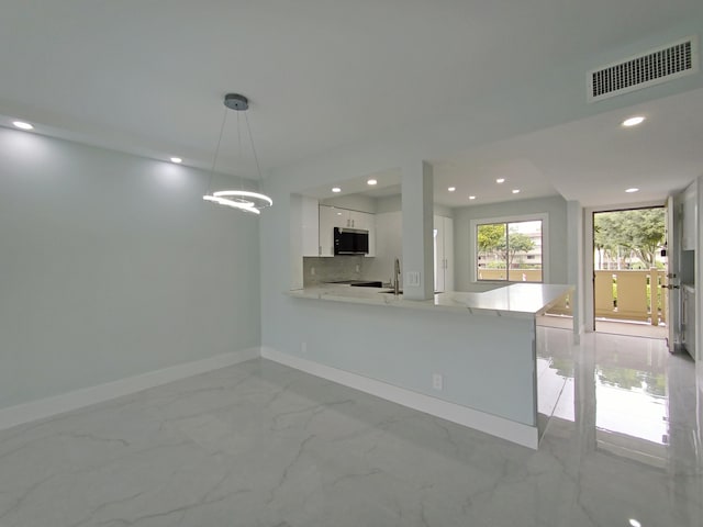 kitchen with kitchen peninsula, decorative backsplash, white cabinetry, and decorative light fixtures