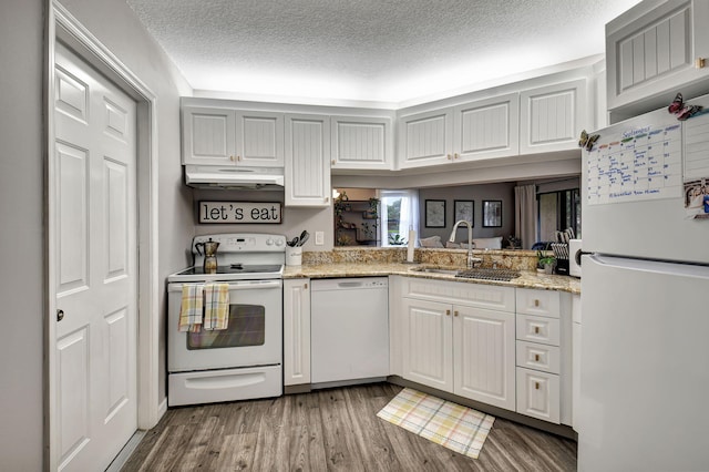 kitchen with white appliances, light stone countertops, a textured ceiling, hardwood / wood-style floors, and sink