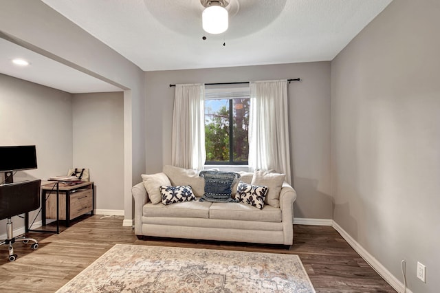 living room with ceiling fan and dark hardwood / wood-style flooring