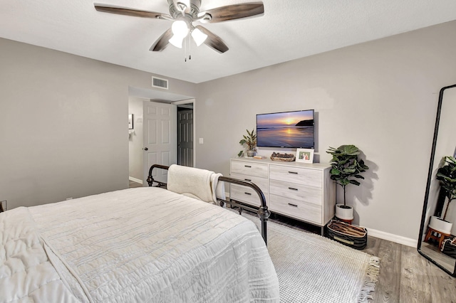 bedroom with a textured ceiling, ceiling fan, and light hardwood / wood-style flooring