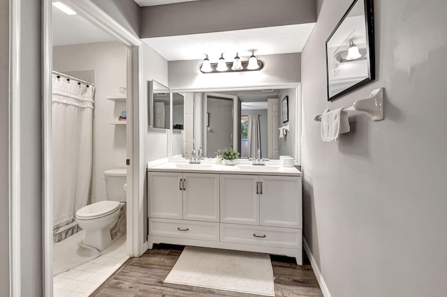 bathroom featuring a textured ceiling, hardwood / wood-style flooring, vanity, and toilet