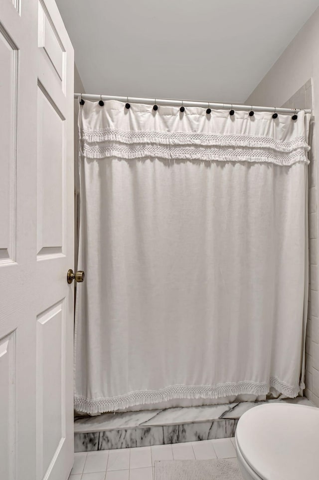 bathroom with a shower with shower curtain, tile patterned flooring, and toilet