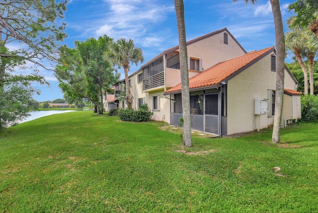 rear view of house featuring a lawn, a water view, and a sunroom