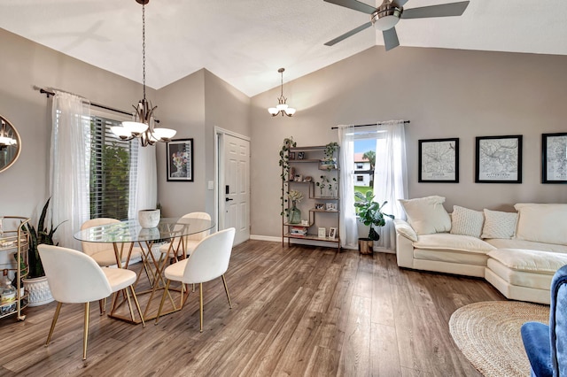 dining room with ceiling fan with notable chandelier, lofted ceiling, and hardwood / wood-style flooring