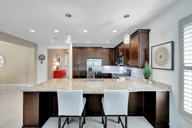 10571 SW Sunray St, Port Saint Lucie, FL 34987 - kitchen with stainless steel appliances, a sink, a peninsula, light stone countertops, and dark brown cabinets
