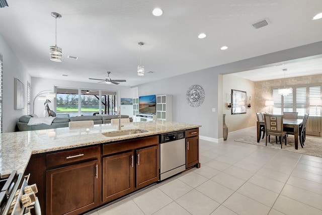 kitchen featuring ceiling fan, light stone countertops, stainless steel dishwasher, sink, and decorative light fixtures