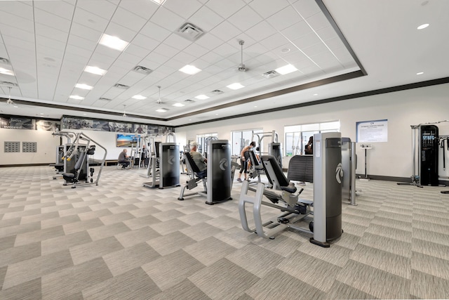 workout area featuring a paneled ceiling, light colored carpet, and a raised ceiling