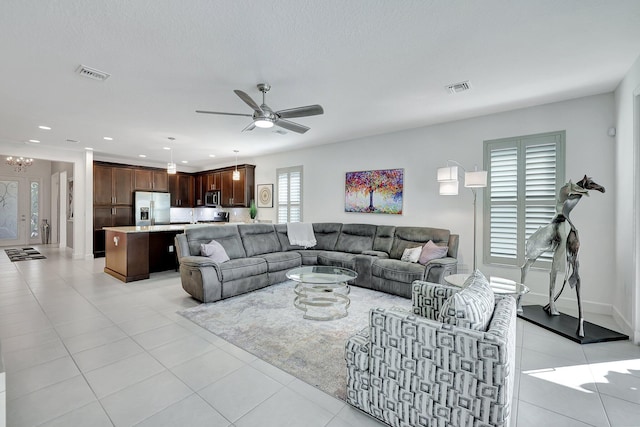 living room with light tile patterned floors, a wealth of natural light, and ceiling fan with notable chandelier