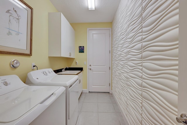 clothes washing area with cabinets, a textured ceiling, light tile patterned flooring, and washer and clothes dryer