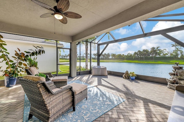 view of patio with a water view, glass enclosure, and ceiling fan