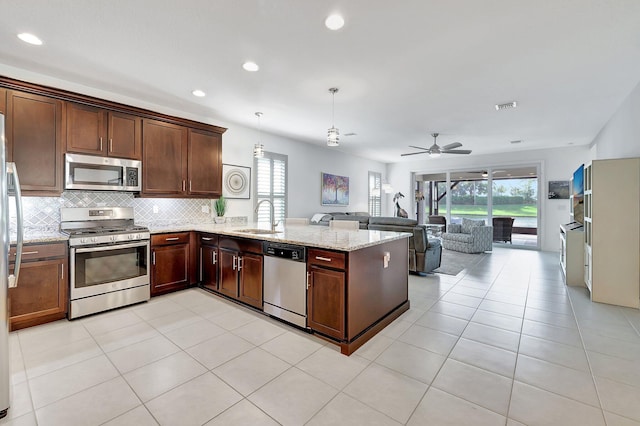 10571 SW Sunray St, Port Saint Lucie, FL 34987 - kitchen featuring stainless steel appliances, a sink, a peninsula, open floor plan, and decorative backsplash